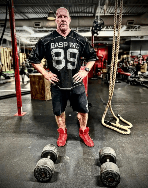 Man standing in gym with dumbbells.
