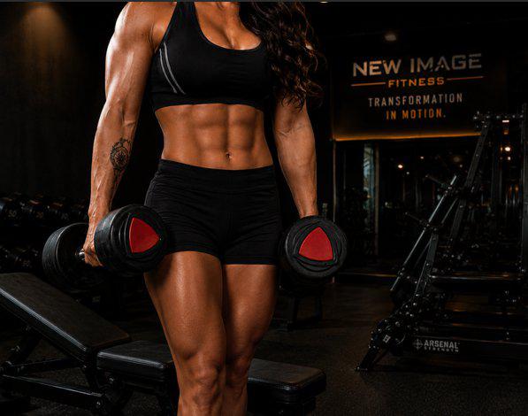 Woman lifting dumbbells in gym setting.
